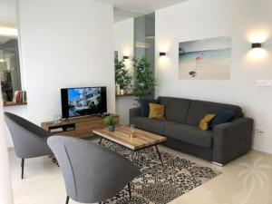 Una sala de estar con un sofá y un televisor. en Beach Avenue Residence, en Arenales del Sol