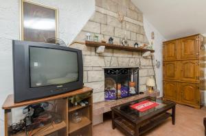 a living room with a tv and a stone fireplace at House Lucica in Splitska +7 photos