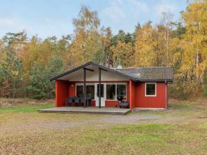 a red cabin with a deck in the woods at Holiday Home Gerty - 300m from the sea in Bornholm by Interhome in Vester Sømarken