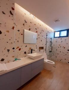 La salle de bains est pourvue d'un mur en pierre, d'un lavabo et de toilettes. dans l'établissement 台東有點田民宿, à Guanshan