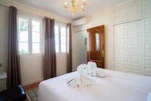un dormitorio con dos cisnes en una cama blanca en Casa Ancladero Big rooftop terrace, 2 bedroom guesthouse w garden and view, en Fuengirola