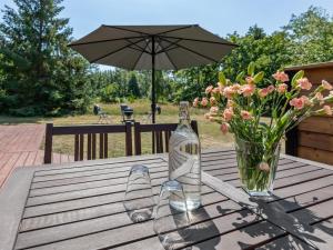 a bottle of wine on a wooden table with a vase of flowers at Holiday Home Selma - 300m from the sea in Bornholm in Vester Sømarken