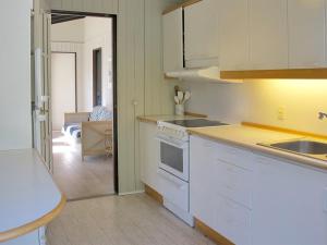 eine Küche mit weißen Schränken und Blick auf ein Wohnzimmer in der Unterkunft Holiday Home Claudette - 1km from the sea in Sealand by Interhome in Hornbæk
