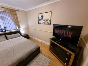 ein Schlafzimmer mit einem Bett und einem Flachbildfernseher in der Unterkunft 6 Bedroom Huge Holiday Home with parking in Luton