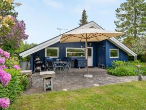 um barracão azul com uma mesa e um guarda-chuva em Holiday Home Begitta - 350m from the sea in Sealand by Interhome em Gilleleje
