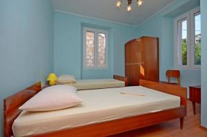 a bedroom with two beds and a blue wall at House Marija in Lastovo