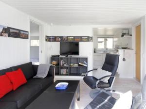 uma sala de estar com um sofá preto e cadeiras em Holiday Home Evert - 250m from the sea in Bornholm by Interhome em Neksø