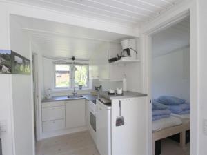 uma cozinha com armários brancos, um lavatório e uma cama em Holiday Home Evert - 250m from the sea in Bornholm by Interhome em Neksø