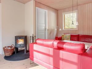 a red couch in a living room with a fireplace at Holiday Home Majken - all inclusive - 300m from the sea by Interhome in Vester Sømarken