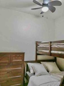 um quarto com uma cama, uma ventoinha de tecto e uma cómoda em MoA S Residences Family Suite with balcony em Manila