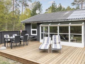 a wooden deck with a table and chairs on it at Holiday Home Henrich - 300m from the sea in Bornholm in Vester Sømarken