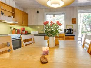 a kitchen with a wooden table with a vase of flowers at Holiday Home Hildegerd - 500m from the sea in Bornholm by Interhome in Vester Sømarken