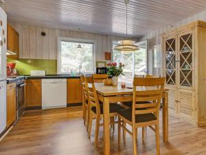 uma cozinha com uma mesa de jantar em madeira e cadeiras em Holiday Home Hildegerd - 500m from the sea in Bornholm by Interhome em Vester Sømarken