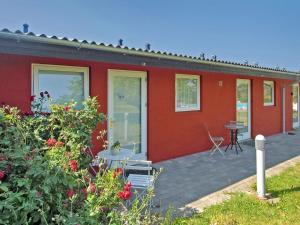 ein rotes Haus mit einer Terrasse und einem Tisch in der Unterkunft Apartment Magnus - 6km from the sea in Bornholm by Interhome in Åkirkeby