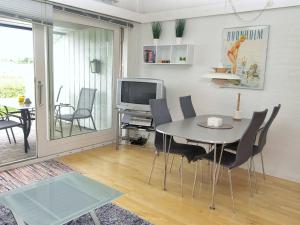uma sala de jantar com uma mesa e cadeiras e uma televisão em Apartment Magnus - 6km from the sea in Bornholm by Interhome em Åkirkeby