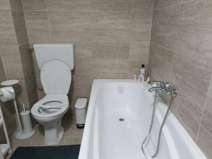 Carmen's nest في Bragadiru: حمام مع حوض استحمام أبيض ومرحاض