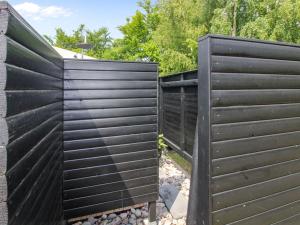 a black fence in a backyard with rocks at Holiday Home Aida - 400m from the sea in Bornholm by Interhome in Rønne