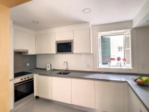 a kitchen with white cabinets and a sink and a window at FX City Lover by LovelyStay in Funchal