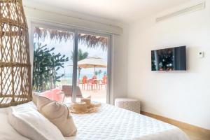1 dormitorio con 1 cama y balcón con sombrilla en Tanusas Retreat & SPA, en Puerto Cayo