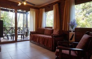uma sala de estar com um sofá e uma varanda em Refugio del Bosque em Carilo