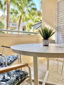 une table et des chaises blanches sur un balcon avec des palmiers dans l'établissement 311 Hastings Street 2 Bedroom Luxury, à Noosa Heads