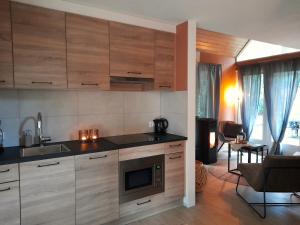 a kitchen with wooden cabinets and a living room at Secret Wellness Droombos in Holten +13 photos