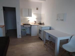 a small kitchen with white cabinets and a table at Oederan One Room Apartment 33m2 Mindestens 1 Monat Reservierung in Oederan