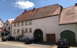 two cars parked in front of a white building at Ferienwohnung Haus Gintz in Blieskastel