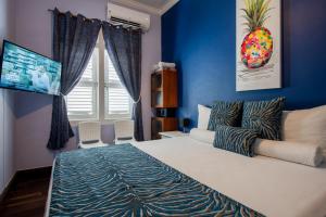 a bedroom with a large bed with blue walls at Villa Amalie & Villa Curiel in Willemstad