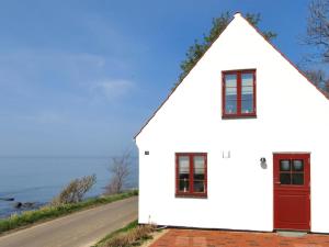 a white house with a red door and a road at Holiday Home Uschi - 15m from the sea by Interhome in Hasle