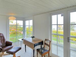 a living room with a table and chairs and windows at Holiday Home Fabine - 50m from the sea by Interhome in Allinge