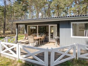 a cottage with a deck and a table and chairs at Holiday Home Mikkelina - 700m from the sea in Bornholm by Interhome in Vester Sømarken