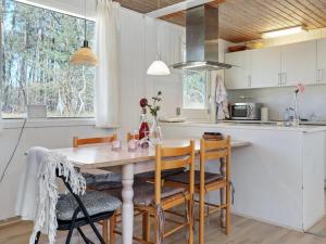 una cucina con tavolo e sedie in legno e una cucina con armadietti bianchi di Holiday Home Mikkelina - 700m from the sea in Bornholm by Interhome a Vester Sømarken