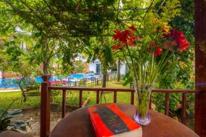 a vase of flowers on a table with a book at Hung Vuong Resort in Phu Quoc