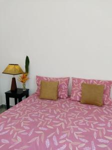 Una cama rosa con dos almohadas encima. en Anusha Apartment 15 Homestay en Galle