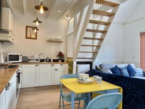 a kitchen and a living room with a yellow table and chairs at Sea Rose Cottage in Kingsdown