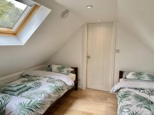 two beds in a attic room with a window at Sea Rose Cottage in Kingsdown