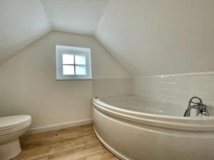 a bathroom with a white tub and a toilet at Sea Rose Cottage in Kingsdown +31 photos