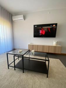 a living room with a glass coffee table and a flat screen tv at Apartamento Central in Braga