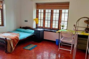a bedroom with a bed and a desk and a table at Ivy Cottage in Mananthavady