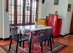 a kitchen with a table and chairs and a refrigerator at Ivy Cottage in Mananthavady