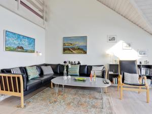 a living room with a black couch and a table at Holiday Home Momo - 10m from the sea in Bornholm by Interhome in Hasle