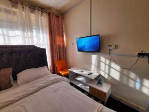 a bedroom with a bed and a tv on the wall at Travelers staycation - 15 Mins to Westlands in Kikuyu