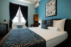 a bedroom with a large bed with blue walls at Villa Amalie & Villa Curiel in Willemstad