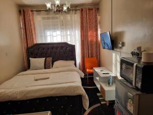 a bedroom with a bed and a television and a window at Travelers staycation - 15 Mins to Westlands in Kikuyu