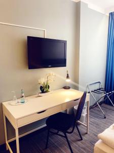 a room with a desk with a tv on the wall at Hotel City Kräme am Römer - Self Check In in Frankfurt/Main