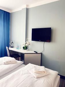 pokój hotelowy z dwoma łóżkami i telewizorem na ścianie w obiekcie Hotel City Kräme am Römer - Self Check In w Frankfurcie nad Menem