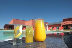 two glasses of orange juice on a table next to a pool at Nawan Resort Serrano in Jesús María