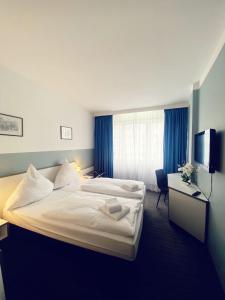 a hotel room with two beds and a television at Hotel City Kräme am Römer - Self Check In in Frankfurt