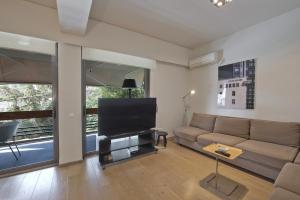 a living room with a couch and a flat screen tv at Sea Breeze Apartment in Athens